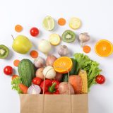 Flat lay with paper bag, vegetables and fruits on white background, copy space