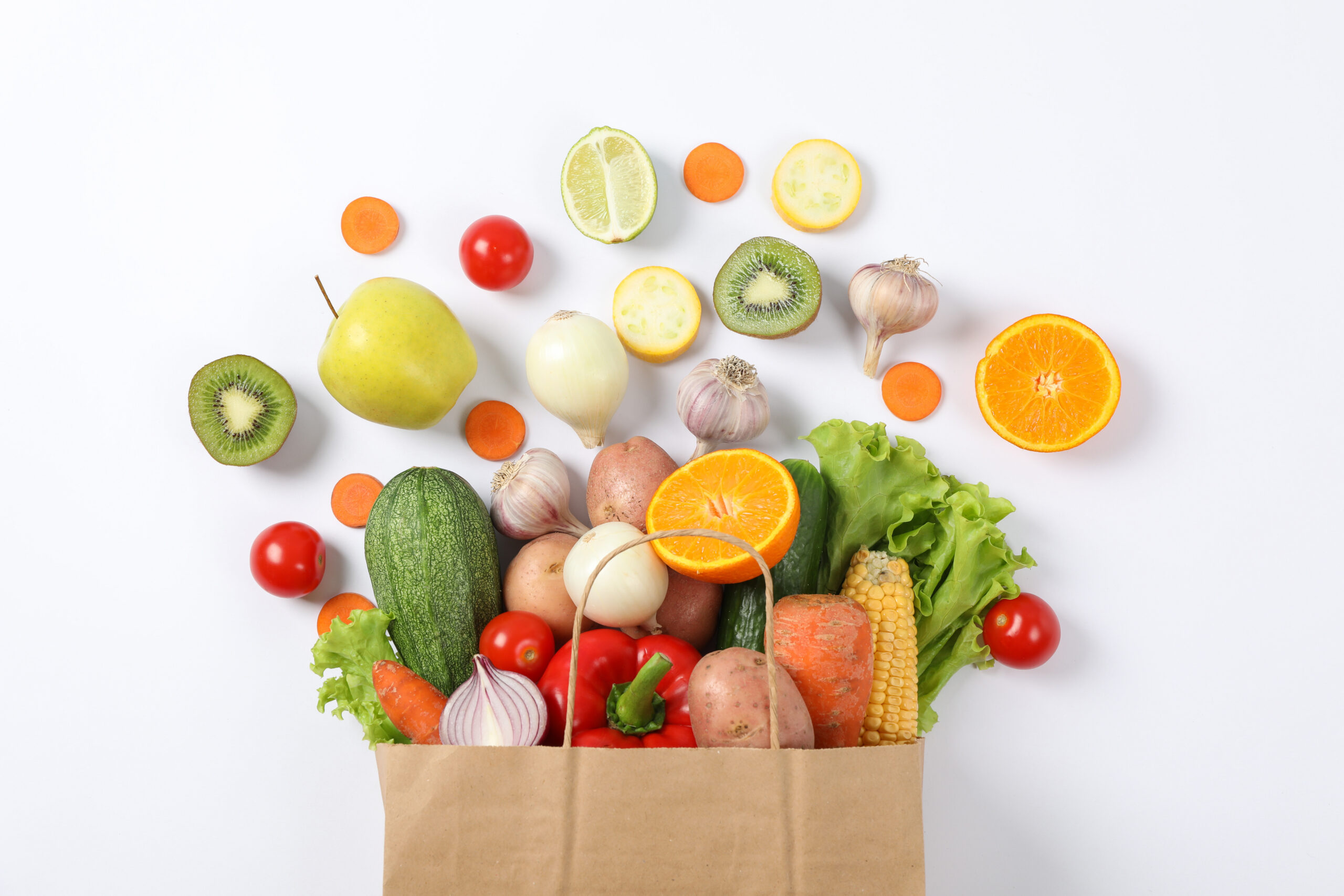 Flat lay with paper bag, vegetables and fruits on white background, copy space